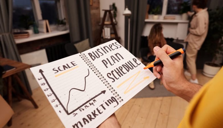 Person holding a notebook with planning details and graph for business strategy indoors.