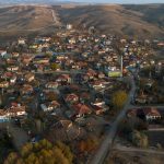 Aerial view of a traditional Turkish village surrounded by hills, showing red-roofed houses, narrow streets, and rural landscape in autumn